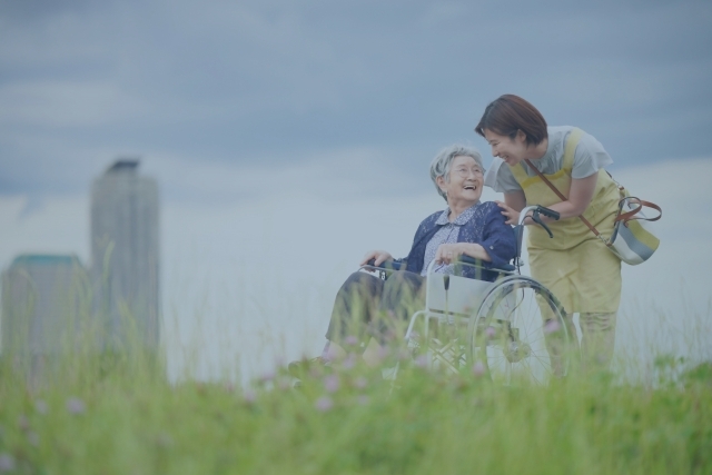 屋外で車椅子に乗ったご高齢女性をサポートする女性看護師の写真
